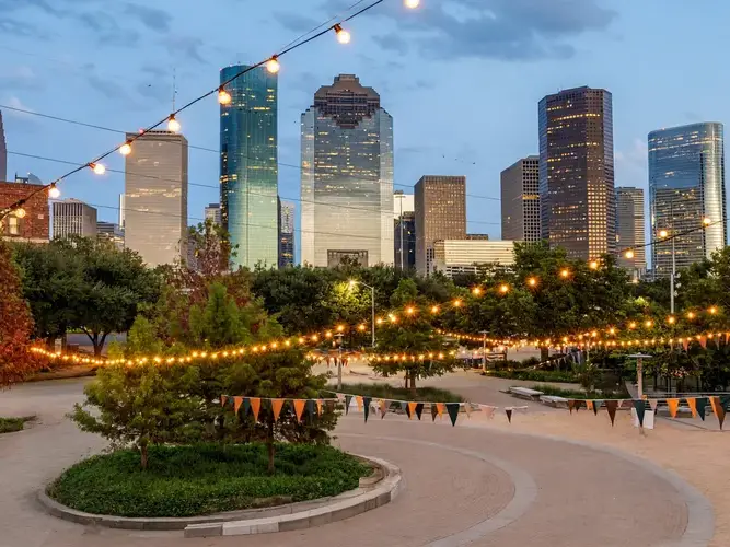 a city park with string lights and a city skyline in the background